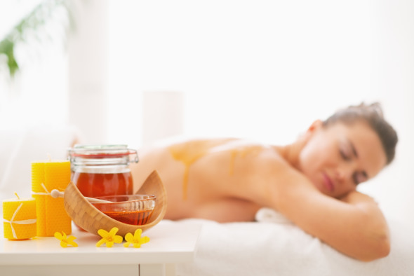Closeup on honey spa therapy ingredients and young woman in background